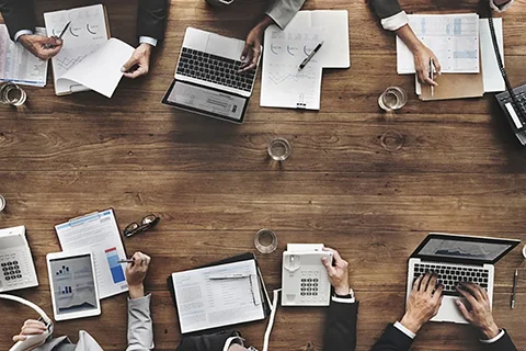 Overhead look at a conference table filled with asset finance professionals working.